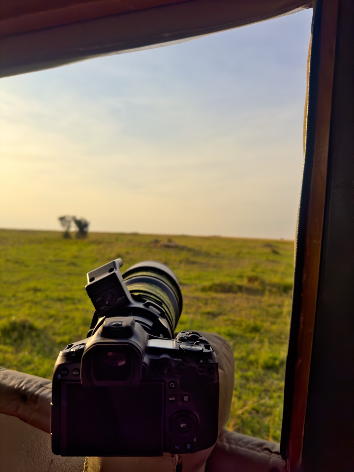 Camera on the door frame of an open jeep, looking out across the plains at last light.