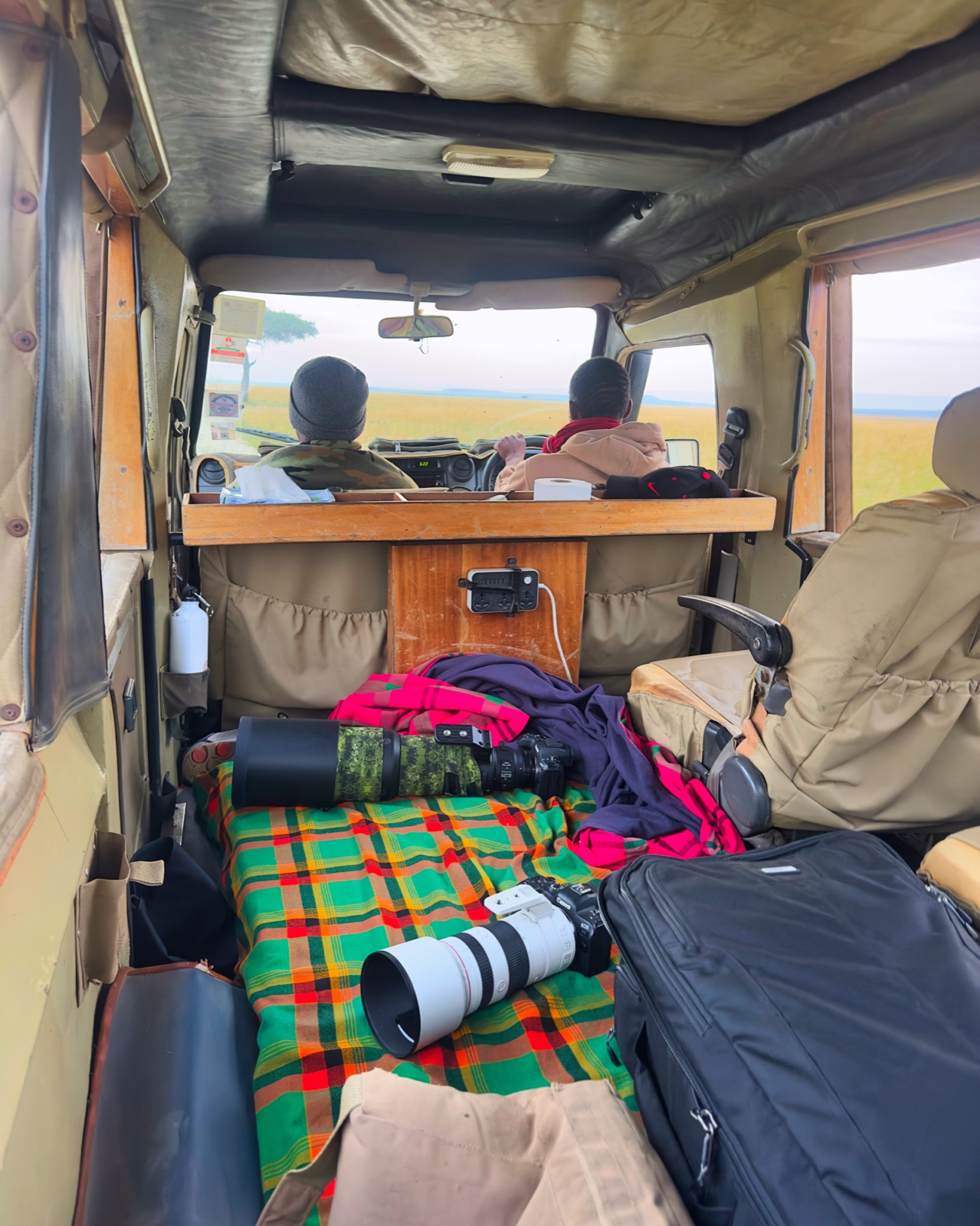 Interior of the working vehicle — bodies, lenses, and kikois across the back bench, the guides up front.